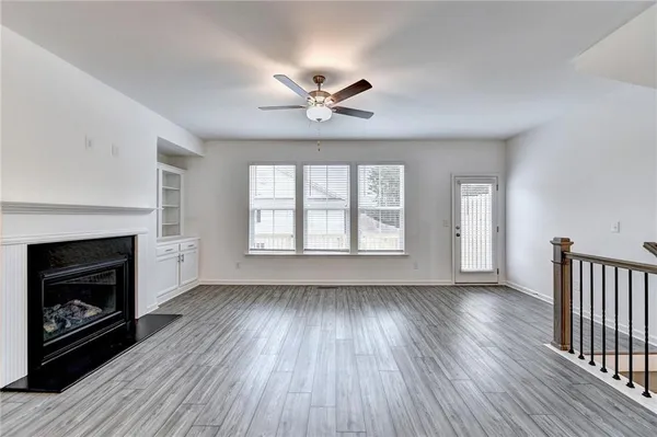 an empty room with windows fireplace and wooden floor