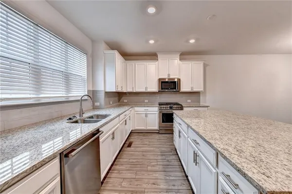 a kitchen with kitchen island granite countertop a sink counter top space a stove and cabinets