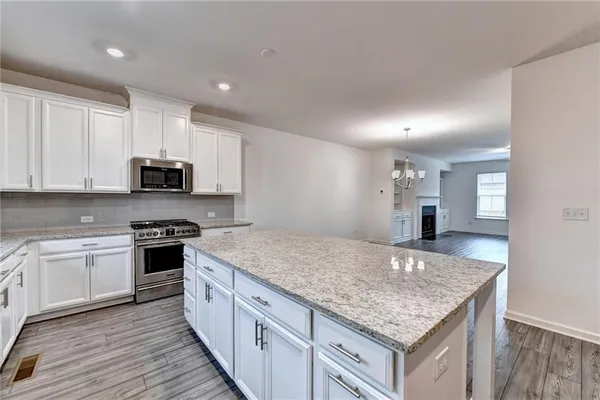 a kitchen with stainless steel appliances granite countertop a stove top oven a sink and white cabinets