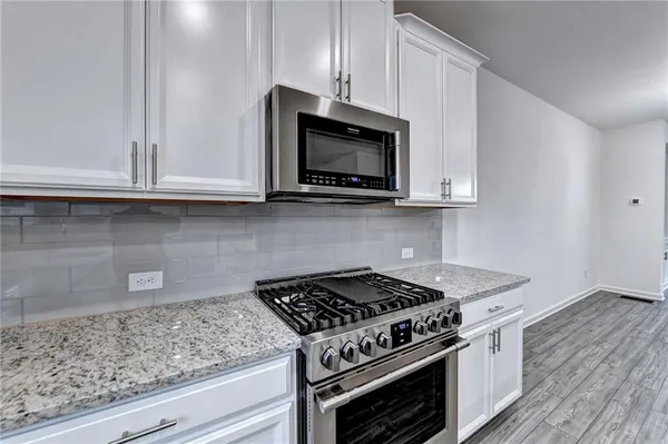 a kitchen with granite countertop white cabinets and stainless steel appliances