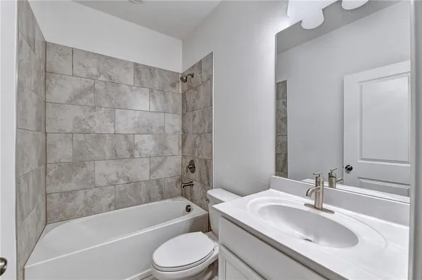a bathroom with a bathtub shower sink vanity mirror and toilet