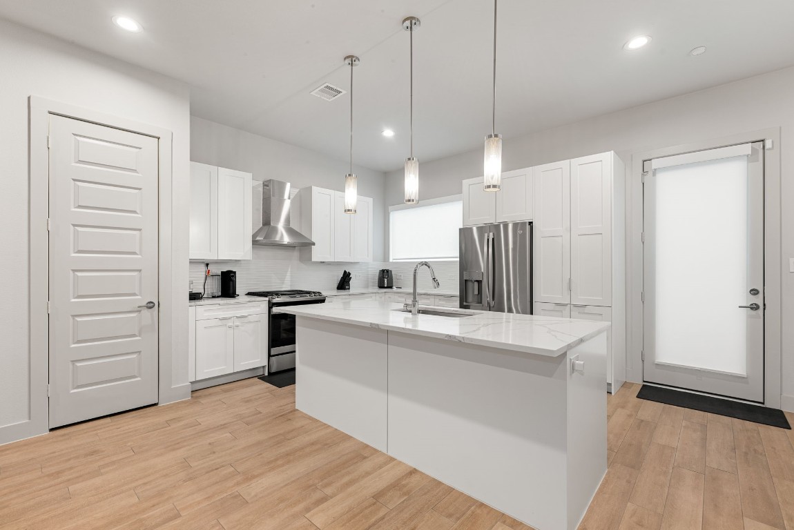 5722 Rucio Lane, Unit A Houston, TX 77092 - Photo 7 of 29 a large white kitchen with kitchen island a stove a sink dishwasher a refrigerator and white cabinets with wooden floor