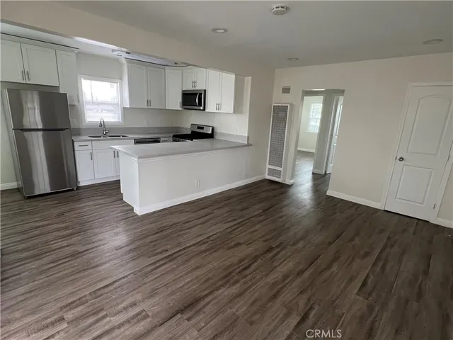 a kitchen with wooden floors white cabinets and stainless steel appliances