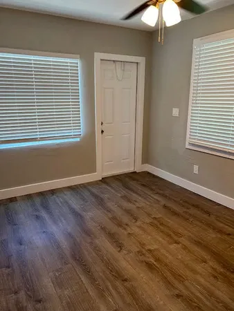 a view of an empty room with wooden floor and a window