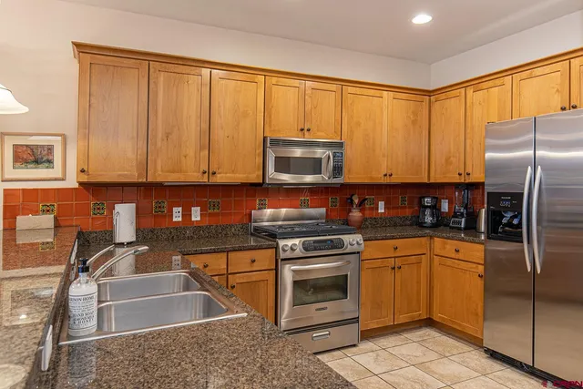 a kitchen with stainless steel appliances granite countertop a stove a sink and a microwave