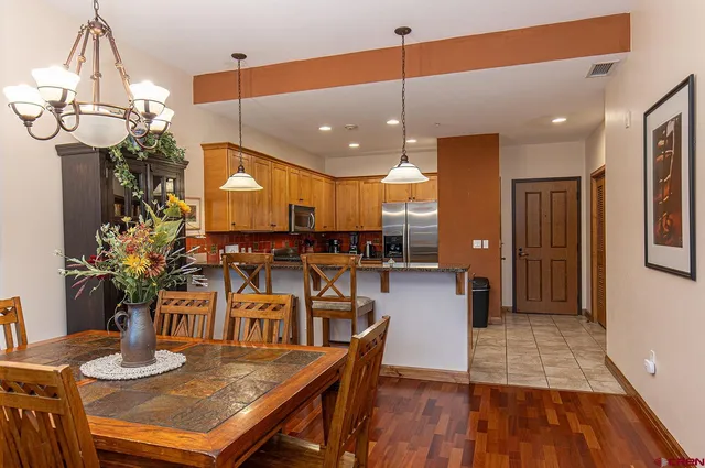 a kitchen with stainless steel appliances kitchen island granite countertop a table chairs and a wooden floor