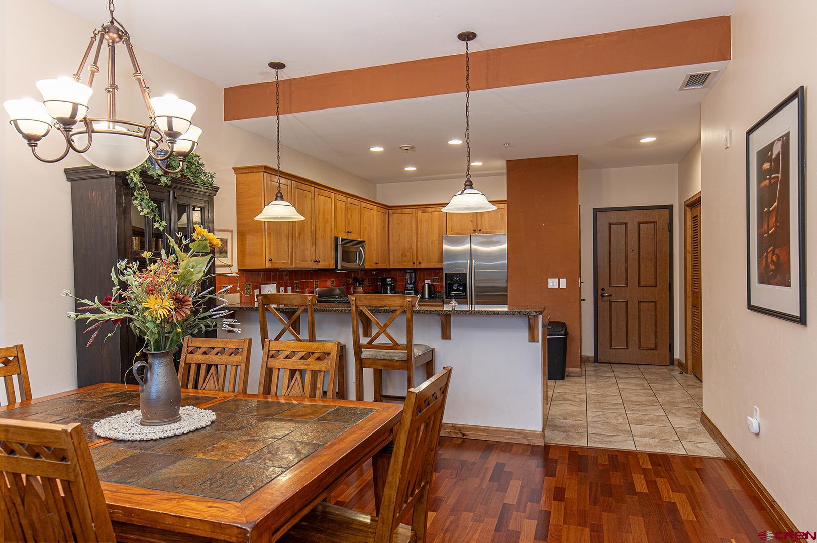 1099 Main Avenue, Unit 410 Durango, CO 81301 - Photo 9 of 34 a kitchen with stainless steel appliances kitchen island granite countertop a table chairs and a wooden floor