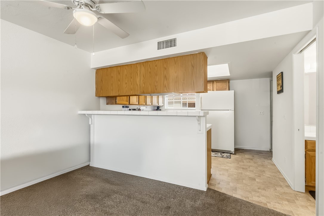 1666 Palma Road Bullhead City, AZ 86442 - Photo 8 of 22 Kitchen with wood finish cabinets, freestanding refrigerator, ceiling fan, a peninsula, and tile countertops
