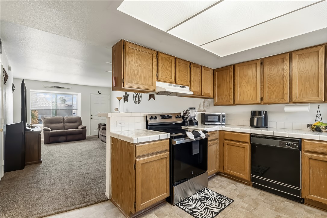 1666 Palma Road Bullhead City, AZ 86442 - Photo 20 of 22 Kitchen with tile countertops, stainless steel appliances, wood finish cabinets, open floor plan, and light colored carpet