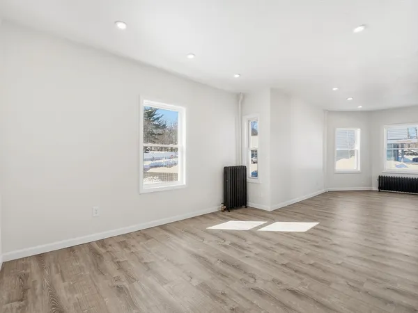 a view of an empty room with window and wooden floor