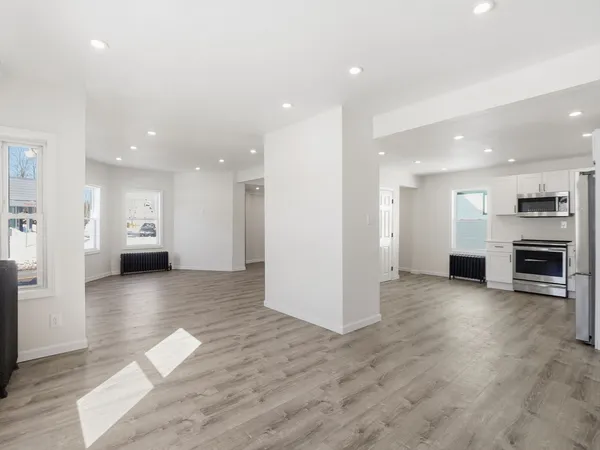 a view of an empty room with a kitchen and a window