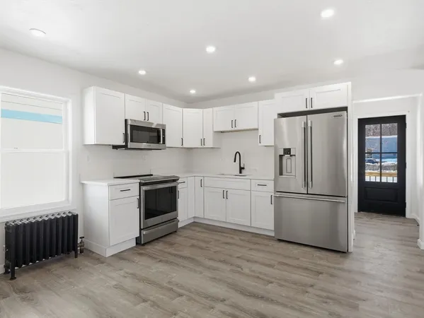 a kitchen with a refrigerator a stove top oven a refrigerator and white cabinets