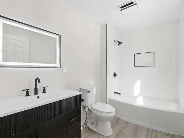 a bathroom with a toilet a sink a mirror and a bathtub