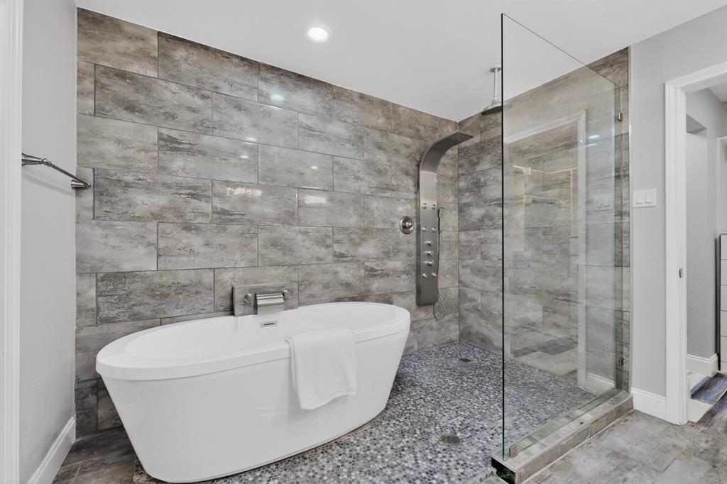 7631 Meadow Road Dallas, TX 75230 - Photo 17 of 40 A bright bathroom showcasing a stylish bathtub and a separate shower with body spray in a sleek glass shower door