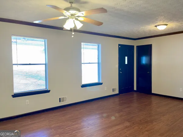 a view of an empty room with window and wooden floor