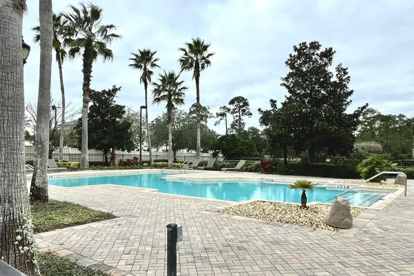 a view of a swimming pool with a yard and palm trees