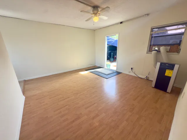 an empty room with wooden floor and windows
