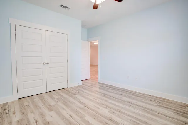 an empty room with wooden floor closet and windows