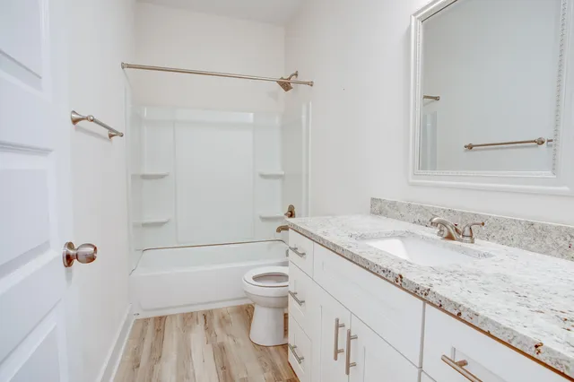 a bathroom with a granite countertop sink a toilet and shower