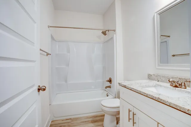 a bathroom with a granite countertop sink toilet mirror and bathtub