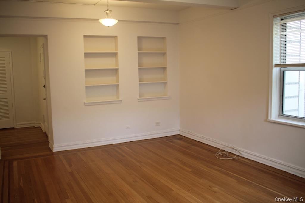 766 Palmer Road, Unit 2F Bronxville, NY 10708 - Photo 16 of 22 Empty room featuring built in shelves and dark wood finished floors