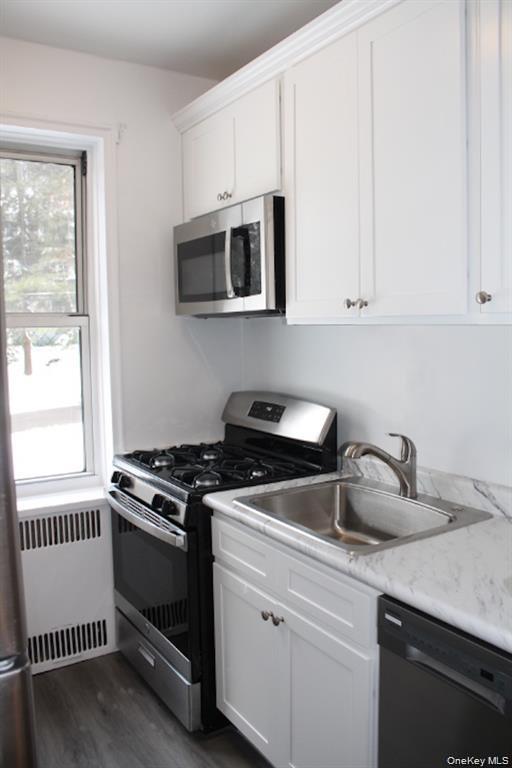 766 Palmer Road, Unit 2F Bronxville, NY 10708 - Photo 6 of 22 Kitchen with appliances with stainless steel finishes, radiator, light countertops, white cabinetry, and dark wood finished floors
