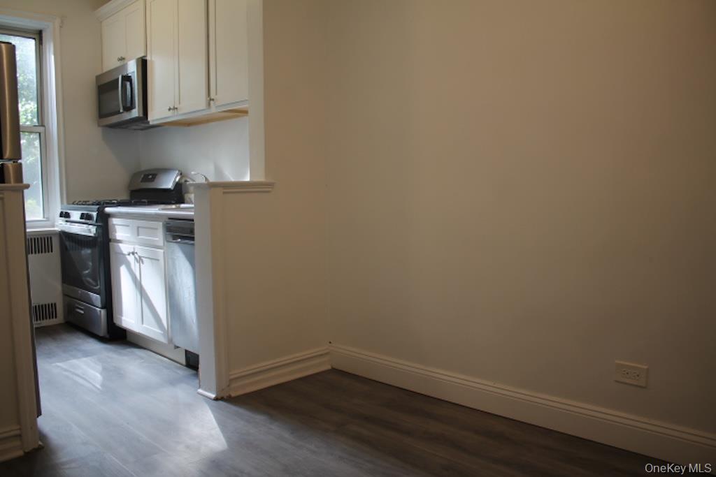 766 Palmer Road, Unit 2F Bronxville, NY 10708 - Photo 7 of 22 Kitchen with white cabinets, stainless steel appliances, dark wood-type flooring, radiator, and light countertops