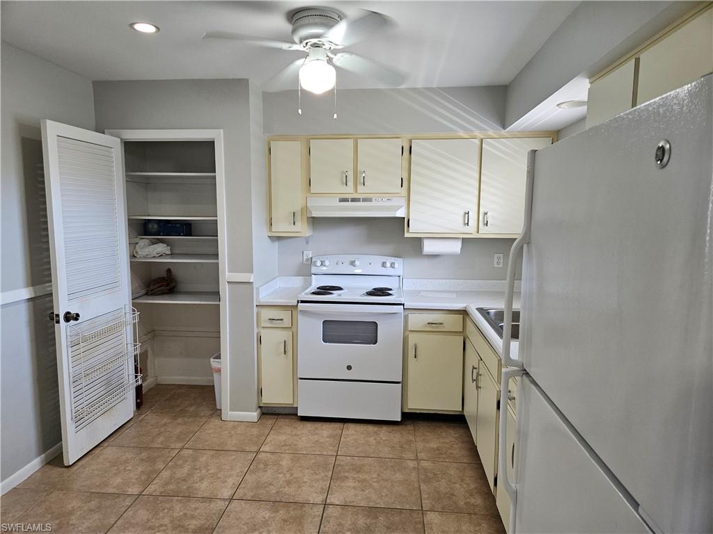 3325 Airport-Pulling Road, Unit D7 Naples, FL 34105 - Photo 4 of 17 Kitchen with ceiling fan, cream cabinets, light tile patterned floors, and white appliances
