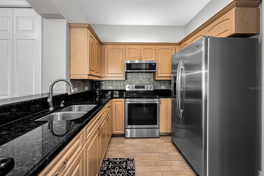 10709 Watula Court New Port Richey, FL 34655 - Photo 56 of 99 a kitchen with stainless steel appliances granite countertop a refrigerator a sink and a stove