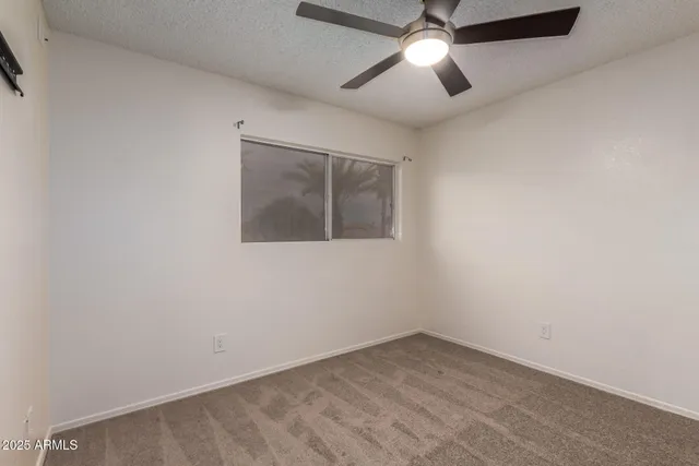 an empty room with a ceiling fan and a window