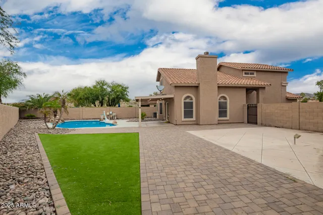 a view of a white house with a yard potted plants and a basket ball poll