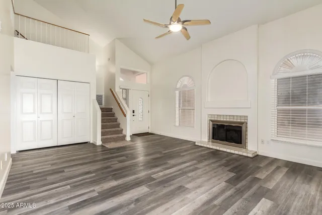 a view of an empty room with wooden floor fireplace and a window