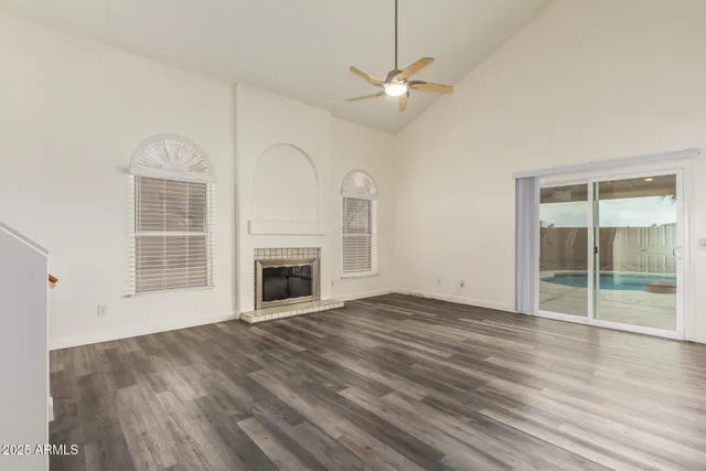 an empty room with wooden floor fireplace and windows