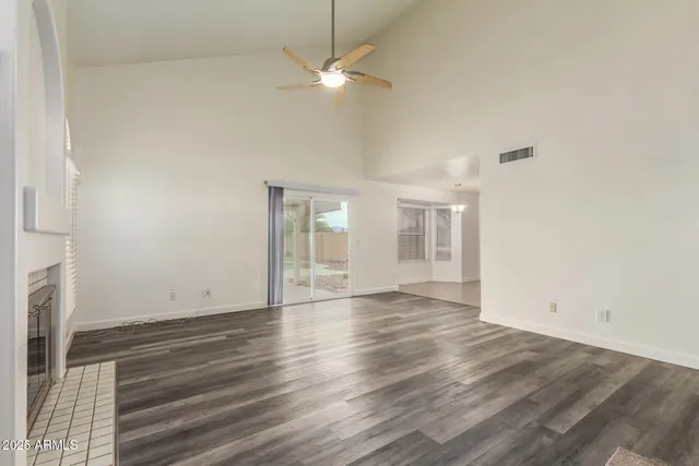 an empty room with wooden floor fan and windows