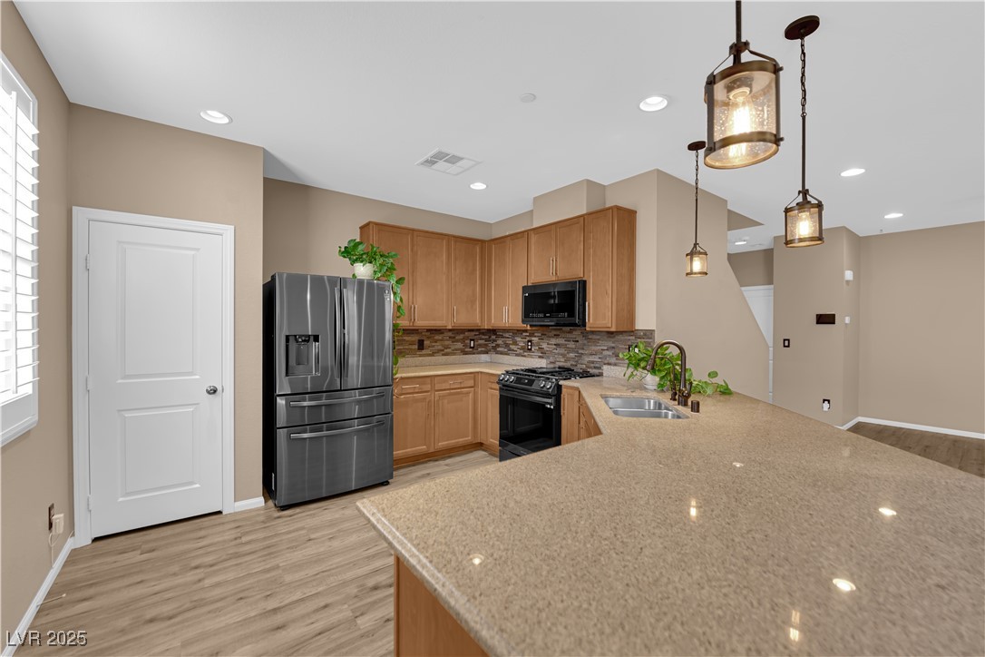 915 Harbor Avenue Henderson, NV 89002 - Photo 6 of 32 Kitchen with black slate stainless appliances, pantry, laminate flooring, backsplash, hanging light fixtures, and recessed lighting