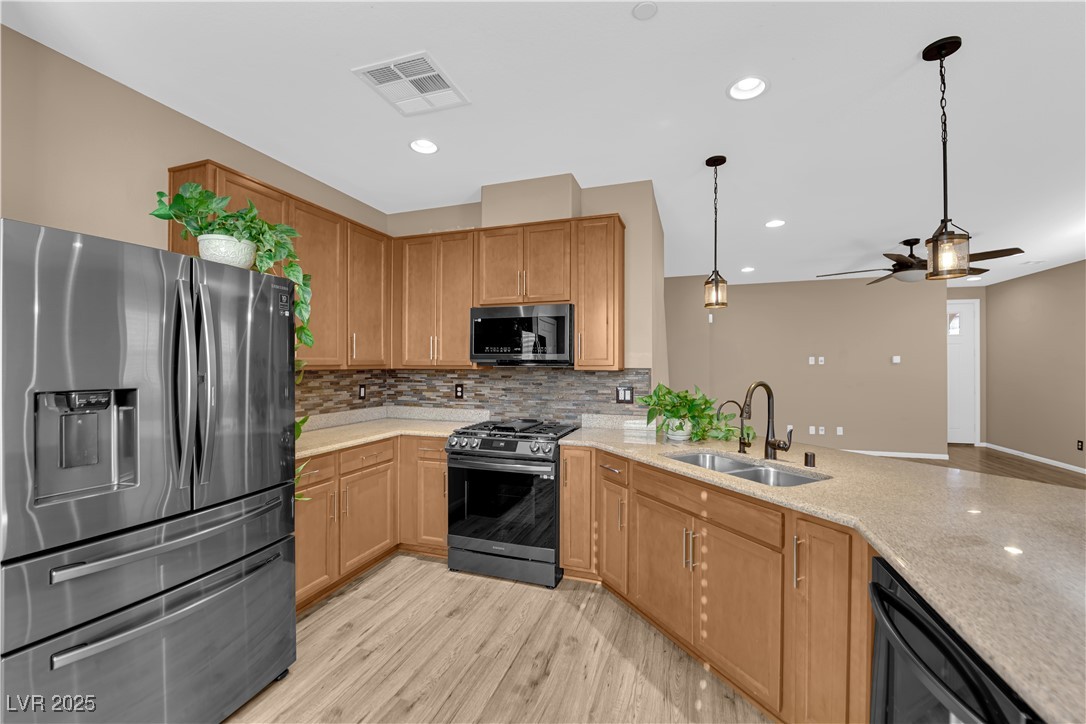 915 Harbor Avenue Henderson, NV 89002 - Photo 7 of 32 Kitchen featuring stainless steel appliances, hanging light fixtures, tasteful backsplash, light stone counters, and a ceiling fan