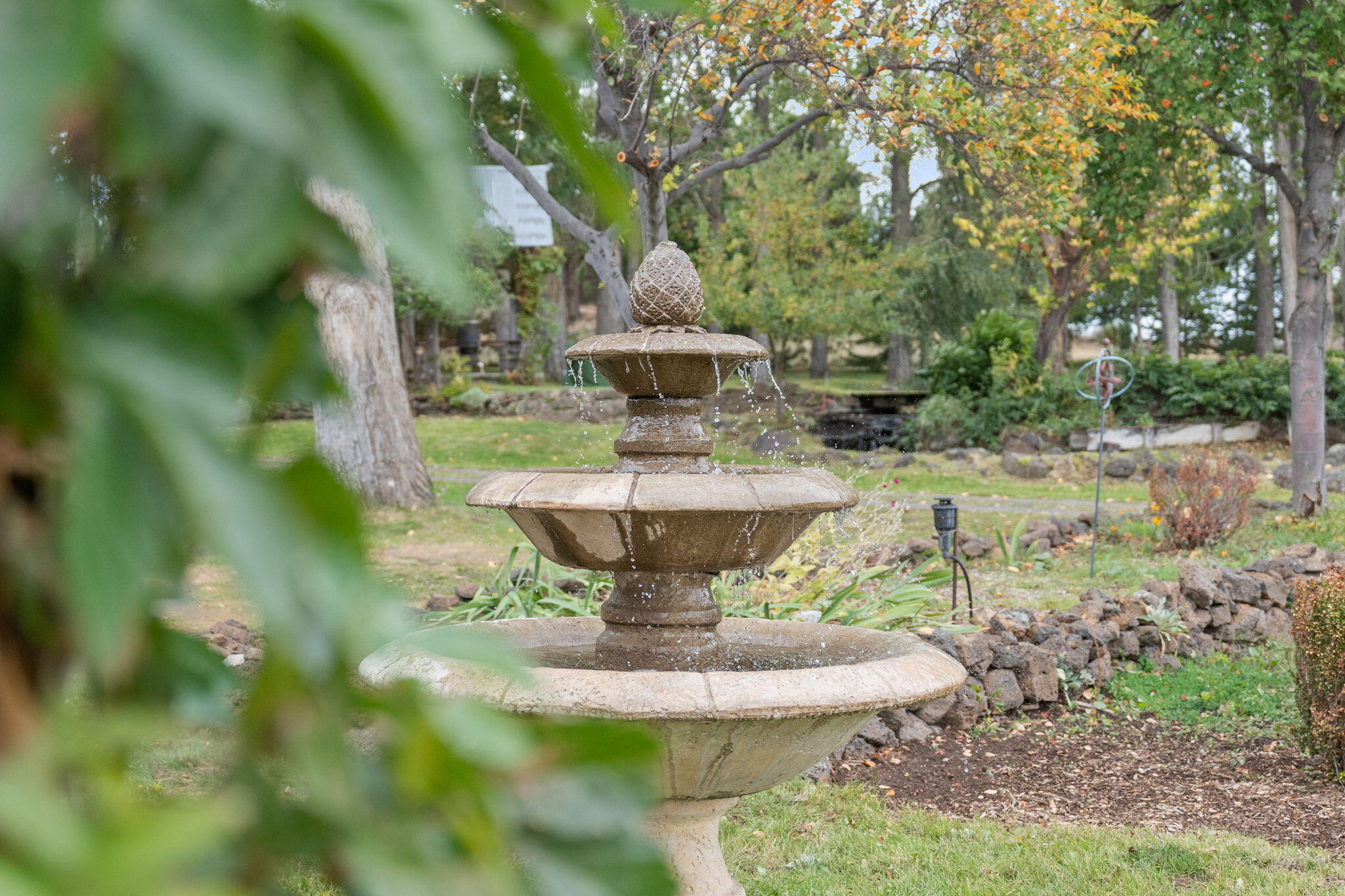 21925 Bear Creek Road Bend, OR 97702 - Photo 91 of 104 a view of a fountain in a yard with large trees