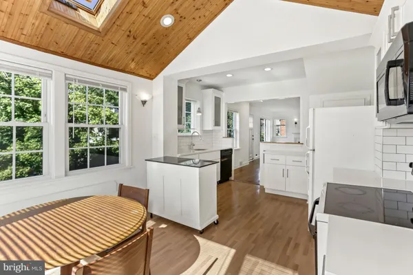 a open kitchen with a sink stove and white cabinets