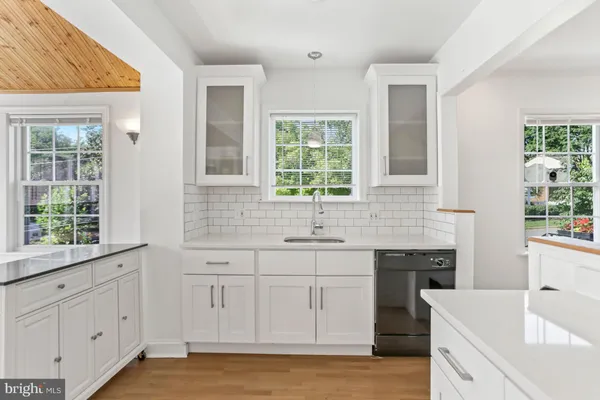 a kitchen with white cabinets and a window
