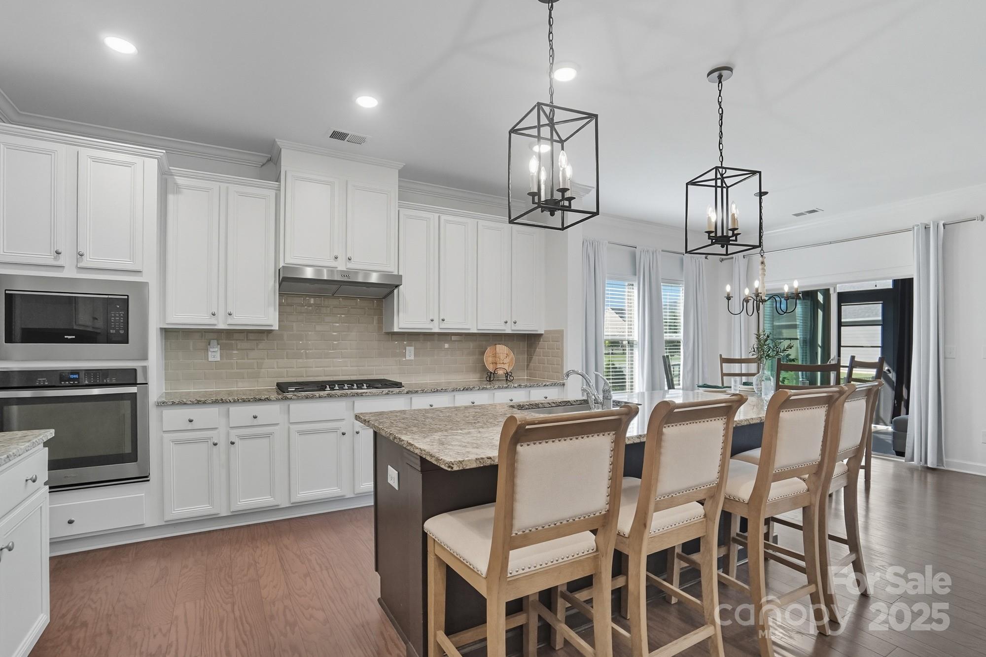 2048 Poplar Ridge Drive Monroe, NC 28110 - Photo 8 of 44 a kitchen with stainless steel appliances kitchen island granite countertop a table and chairs in it