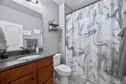 a bathroom with a granite countertop toilet sink and mirror