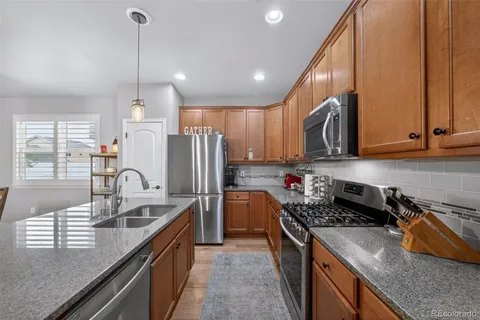 a kitchen with stainless steel appliances granite countertop a sink a stove and a refrigerator