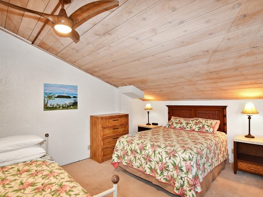 1661 Pee Road, Unit I303 Koloa, HI 96756 - Photo 8 of 15 a bedroom with a large bed and a chandelier