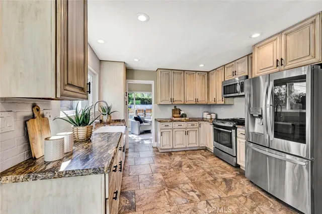 a kitchen with granite countertop a stove a sink and a refrigerator