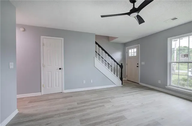 a view of a hallway with wooden floor and a ceiling fan
