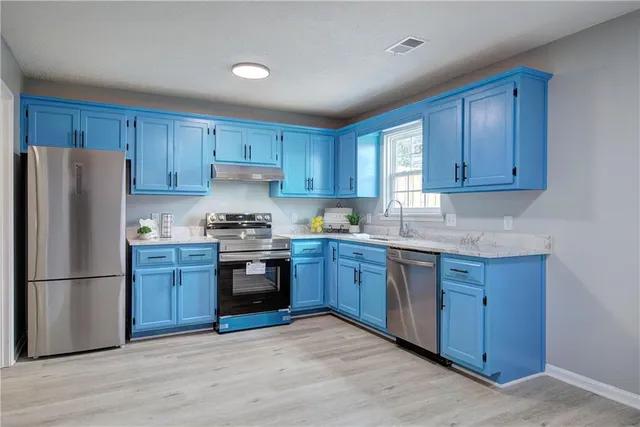 a kitchen with granite countertop wooden cabinets stainless steel appliances and a window