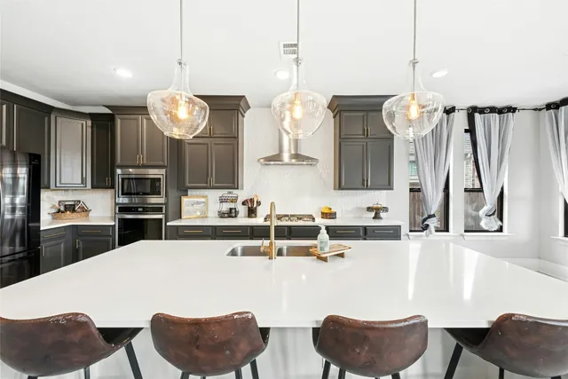 a kitchen with stainless steel appliances kitchen island granite countertop a sink dishwasher a dining table and chairs with wooden floor