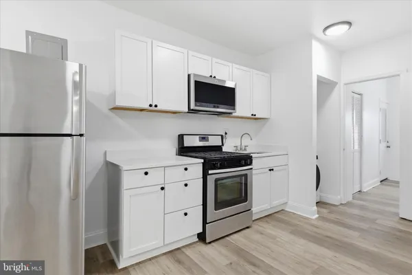 a kitchen with stainless steel appliances granite countertop a refrigerator stove and white cabinets