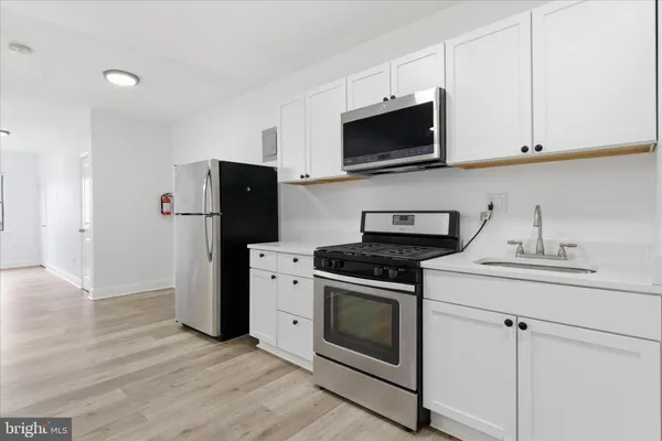 a kitchen with stainless steel appliances granite countertop white cabinets a stove a microwave and a refrigerator