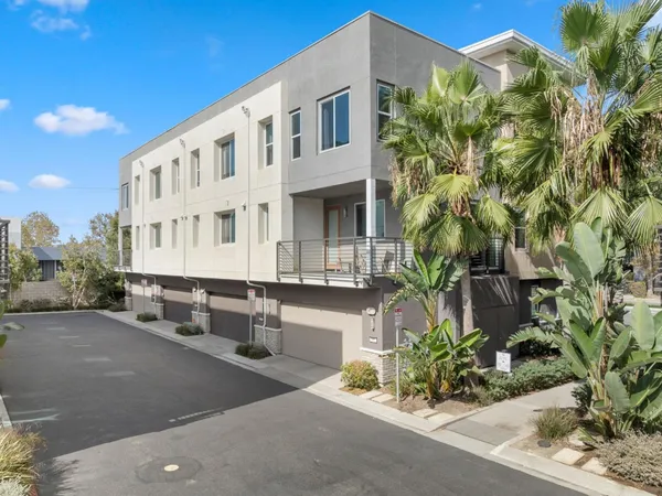 a front view of a multi story residential apartment building with yard and parking